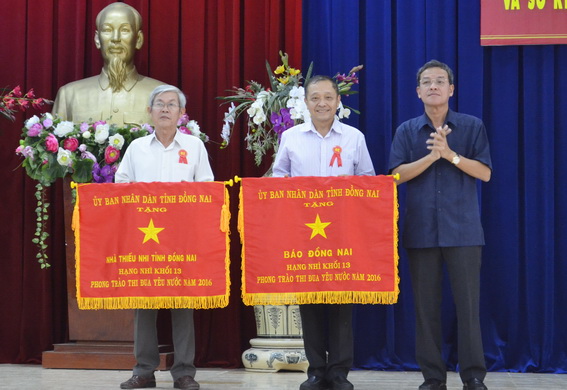 Chủ tịch UBND tỉnh Đinh Quốc Thái trao cờ thi đua xuất sắc hạng nhì cho Báo Đồng Nai và Nhà thiếu nhi tỉnh Đồng Nai có thành tích xuất sắc trong phong trào thi đua yêu nước năm 2016