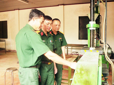 Thiếu tá Lê Đình Thuận (giữa) cùng cán bộ đi kiểm tra máy móc khu vực ép nhựa lựu đạn. 