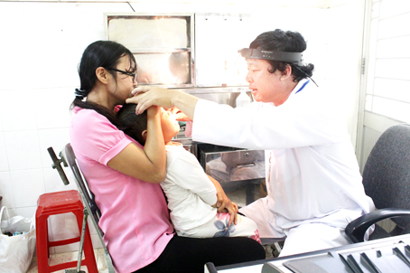 Bác sĩ Ngô Văn Phan, Khoa Tai mũi họng Bệnh viện nhi đồng Đồng Nai, khám bệnh cho một bệnh nhi. Ảnh: An An