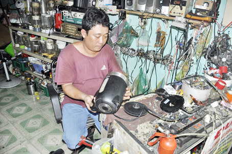 Ông Võ Văn Đức đang cặm cụi sửa món đồ điện tử để kịp giao cho khách.