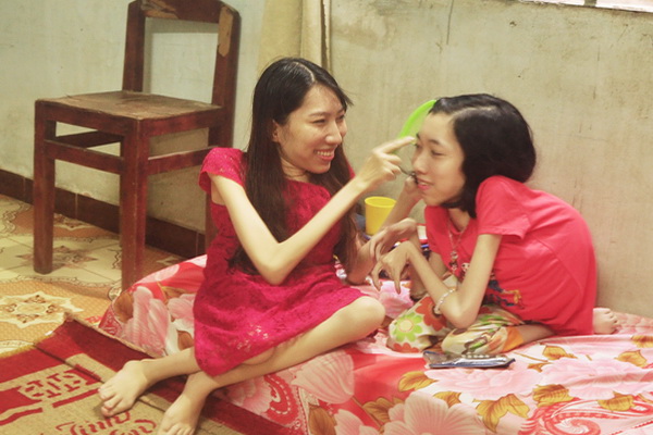 Chị Phạm Tuyết Trinh (trái) chơi với em gái ruột cũng bị khuyết tật.