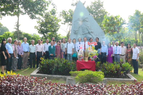 các đại biểu chụp hình lưu niệm bên bức phù điêu của Thi tướng Huỳnh Văn Nghệ nằm trong Vườn tượng Danh nhân văn hóa Trấn Biên.