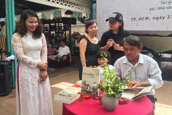 Nhà văn Nguyễn Trí ký tặng sách cho độc giả tại đường sách Nguyễn Văn Bình.