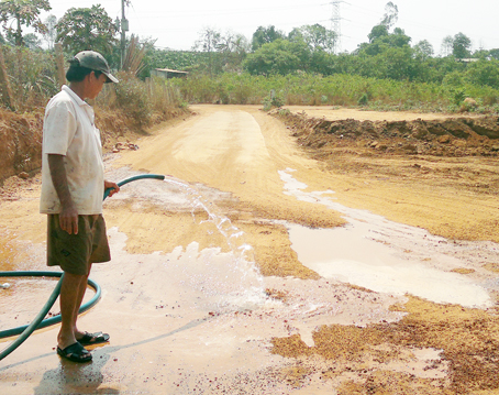 Sau khi đất bị khai thác, xe ben chạy liên tục gây bụi bặm, người dân phải tưới nước để ngăn những cơn “bão” bụi ảnh hưởng đến cuộc sống.