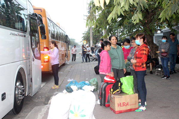 Cảnh công nhân chuẩn bị hành lý, lên xe về quê đón Tết trước cổng Công ty cổ phần Taekwang Vina Industrial sáng sớm ngày 11-2.