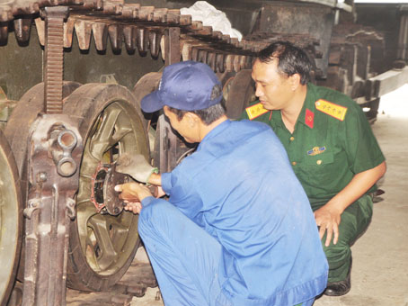 Đại úy Phạm Văn An (phải) hướng dẫn thợ sửa chữa dùng vam cảo tháo bánh tỳ xe PTS, GSP.