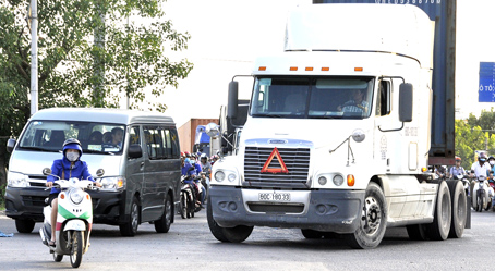 Một người điều khiển xe máy chạy vượt lên trước đầu xe ô tô, xe container tại khu vực cầu Sập (TP.Biên Hòa).