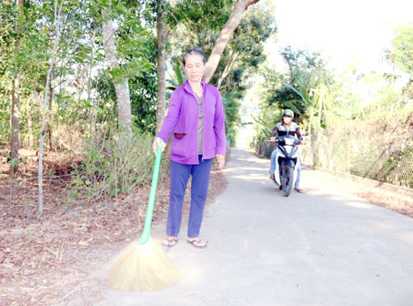 Bà Trần Thị Xuân (ngụ ấp Thọ Lâm 2, xã Phú Thanh, huyện Tân Phú) dọn dẹp phần đường ngang qua nhà mình.
