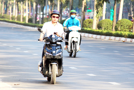 Một người vừa sử dụng điện thoại vừa lái xe máy trên đường Đồng Khởi (TP.Biên Hòa).(Ảnh chụp vào ngày 11-3-2018)