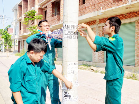 Dân quân phường Bửu Long (TP.Biên Hòa) tham gia cạo, bóc các tờ rơi quảng cáo dán trái phép. ảnh: Đ.Tùng