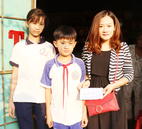 Bà Nguyễn Thị Thu Phương (xã Gia Canh, huyện Định Quán) (bên phải) trao quà cho một học sinh nghèo tại xã Phú Lợi chiều 3-4.