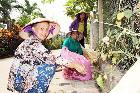 Bà Sáu (bìa trái) cùng chị em phụ nữ trong tổ môi trường ấp Xóm Hố quét dọn đường trong xóm.