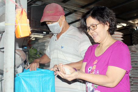 Bà Liêu Thị Hiệp (phải) kiểm tra chất lượng gạo sau khi xay xát.