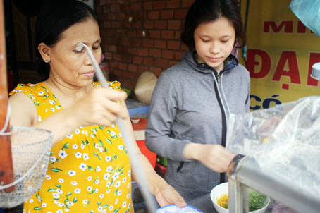 Tranh thủ ngày nghỉ hè, sinh viên Trường đại học Đồng Nai Phạm Kim Thảo (phải) phụ  bán hủ tiếu gõ kiếm thêm thu nhập.