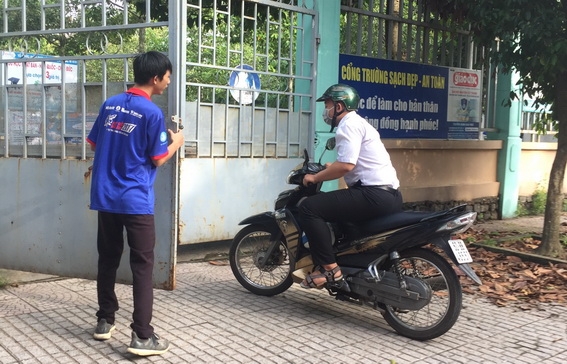 Sinh viên tình nguyện mở cổng cho một thí sinh của Trung tâm giáo dục thường xuyên huyện Trảng Bom đi thi trễ