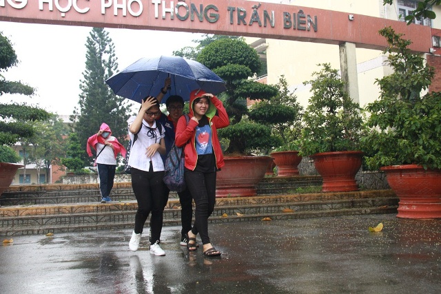 Hai nữ sinh được sinh viên tình nguyện hỗ trợ rời phòng thi khi trời mưa