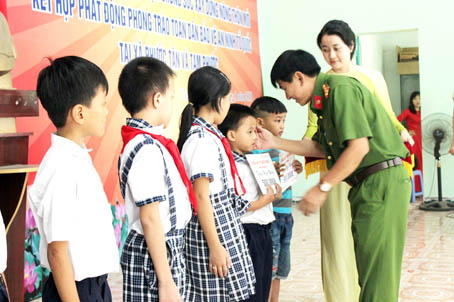 Đại tá Bùi Hữu Danh, Phó giám đốc Công an tỉnh tặng quà cho học sinh nghèo vượt khó trong đợt ra quân phát động phong trào ở 2 xã Tam Phước và Phước Tân và tháng 4-2018. Ảnh: Tố Tâm