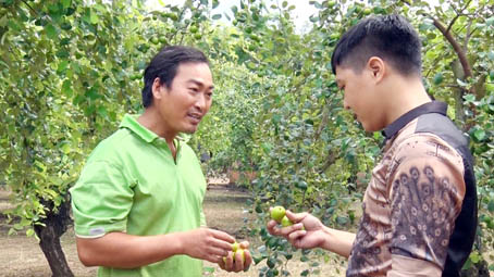 Ông Lê Văn Lợi (trái) giới thiệu cho du khách tại vườn táo của gia đình tại xã Sông Nhạn, huyện Cẩm Mỹ.