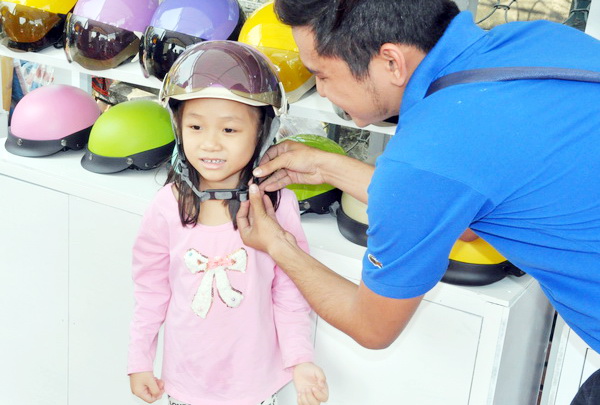 Phụ huynh chọn mũ bảo hiểm đạt chuẩn chất lượng cho trẻ em tại một điểm đổi mũ bảo hiểm đạt chuẩn ở TP.Biên Hòa.