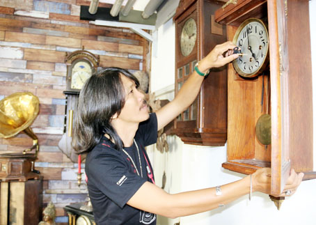 Ông Nguyễn Văn Hòa (ngụ huyện Trảng Bom) đang lên dây cho chiếc đồng hồ quả lắc trên 80 năm tuổi.