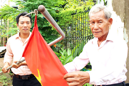 Già làng Nguyễn Văn Long (phải) cùng người dân làng dân tộc Chơro treo cờ Tổ quốc trên những tuyến đường mới.