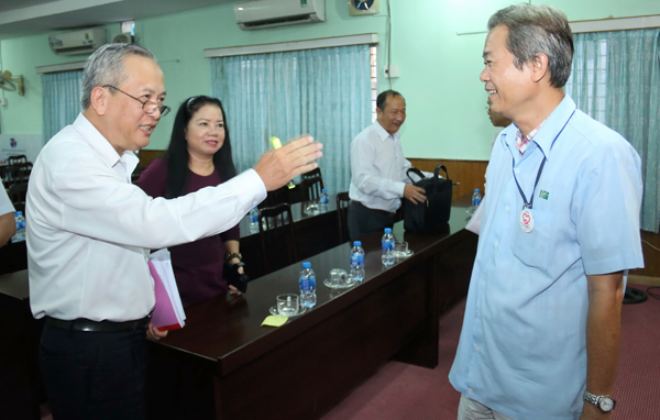 Chủ tịch Hội đồng an toàn, vệ sinh lao động tỉnh, Giám đốc Sở Lao động - thương binh và xã hội Huỳnh Văn Tịnh (bên trái) trao đổi cùng đại diện doanh nghiệp bên lề hội nghị.