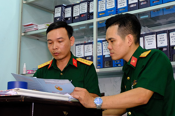 Đại úy Trần Văn Hà (trái) trao đổi nội dung bài giảng chính trị với đồng nghiệp. Ảnh: Đăng Tùng
