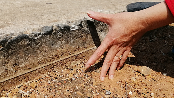 Chị Nguyễn Thị Hiền đang dùng tay đo độ cao chênh lệch giữa đường và lề đường