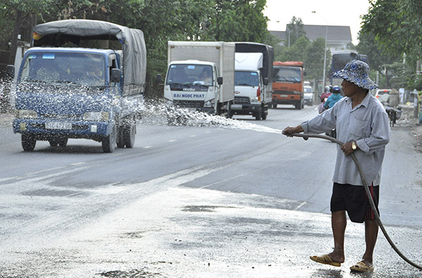  Nhiều người dân sống ven đường Bùi Hữu Nghĩa phải tự tưới nước trên đường để hạn chế ô nhiễm bụi