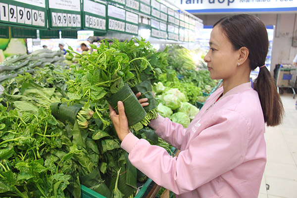Khách hàng chọn mua rau được gói bằng lá chuối tại Co.opmart Biên Hòa. Ảnh: H.Quân