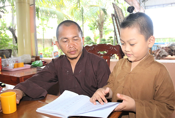 Đại đức Thích Trung Điền kiểm tra việc học tập của một cháu bé đang được nuôi dưỡng tại chùa. Ảnh: Văn Truyên