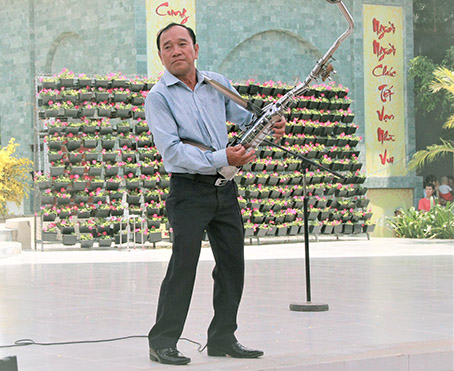 Nghệ sĩ Mai Đình Tới biểu diễn nhạc cụ do ông sáng tạo từ ống pô xe máy trước khán giả Đồng Nai. ảnh: V.Truyên