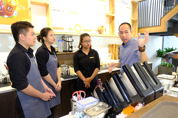 Anh Hà Vũ Bảo Giang (phải) hướng dẫn nhân viên các bước phục vụ khách hàng. Ảnh: M.Thành