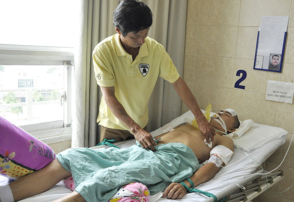 Ông Nguyễn Đăng Trường chăm sóc con trai là N.Đ.P. (21 tuổi, quê ở tỉnh Quảng Trị) đang được điều trị chấn thương sọ não tại Bệnh viện đa khoa Đồng Nai. Ảnh: T.Hải