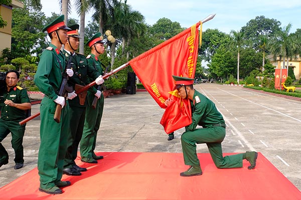 Chiến sĩ mới có thành tích huấn luyện tốt thực hiện nghi thức hôn quân kỳ trong buổi lễ