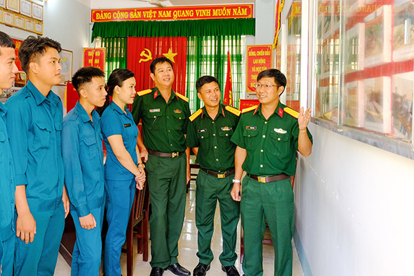 Trung tá Lê Ngọc Chánh (bìa phải), Chính trị viên phó kiêm Trưởng ban Chính trị Ban Chỉ huy quân sự huyện Xuân Lộc giới thiệu hình ảnh hoạt động của lực lượng vũ trang huyện. Ảnh: Đ.PHÚ