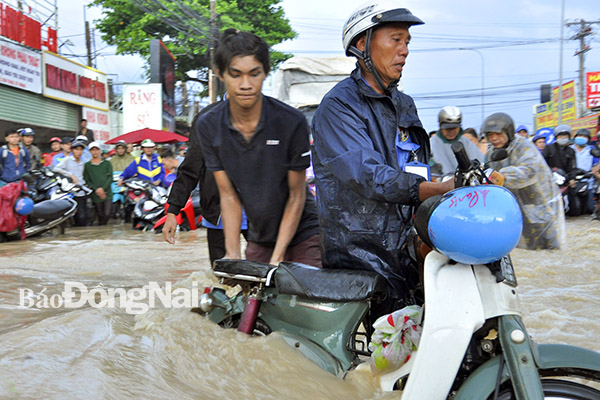 Một chiếc xe máy bị dòng nước cuốn trôi, may mắn được người dân kéo lại trên đường Bùi Văn Hòa (gần khu vực Cổng 11)