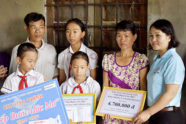 Đại diện nhóm thực hiện chương trình Tiếp bước ước mơ (bìa phải) Đài Truyền thanh huyện Định Quán trao quà cho gia đình một học sinh nghèo ở xã Gia Canh