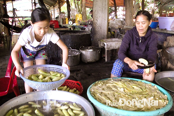 Em Trần Thị Phương Liên, học sinh lớp 4/2 Trường tiểu học Xuân Trường (huyện Xuân Lộc) phụ mẹ làm chuối sấy để bán trên núi Chứa Chan