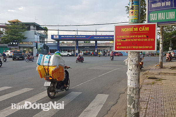 Một trụ đèn giao thông trên đường Dương Tử Giang (TP.Biên Hòa) chằng chịt các loại tờ rơi quảng cáo dù đã có biển cảnh báo. Ảnh: L.Phương. (Ảnh chụp ngày 30-7-2019)