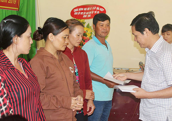 Ông Trần Quang Tú, chủ tịch UBND huyện Định à quán tặng quà cho người dân