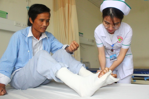 Điều dưỡng kiểm tra vết thương ở cổ chân cho anh H. trước khi bệnh nhân xuất viện.