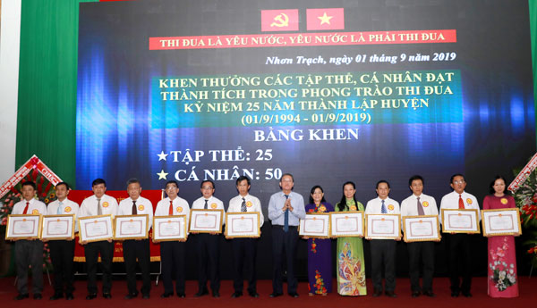 Nguyên Chủ tịch UBND tỉnh Đinh Quốc Thái trao bằng khen của UBND tỉnh cho các tập thể có thành tích trong phong trào kỷ niệm 25 ngày thành lập huyện Nhơn Trạch. Ảnh: Huy Anh