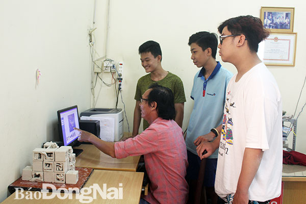 Thầy Phạm Công Hoàng cùng sinh viên thực hiện các thao tác đồ họa trên máy tính trước khi in 3D. Ảnh: M.ANH