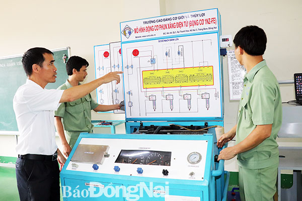 Nhóm tác giả Cao Văn Tuyền, Đỗ Cao Nguyên và Phạm Xuân Huyên và mô hình động cơ phun xăng điện tử dùng trong dạy nghề sửa chữa ô tô. Ảnh: H.Yến