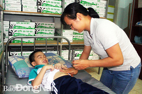 Một học sinh bị đau bụng được chăm sóc tại phòng y tế của Trường tiểu học Phan Đình Phùng, TP.Biên Hòa