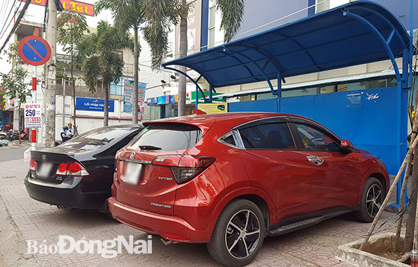 Hai chiếc ô tô đậu ngay trước khu vực nhà chờ xe buýt trên vỉa hè đường Phạm Văn Thuận (TP.Biên Hòa). Điều này ảnh hưởng tới việc đón xe buýt của người dân