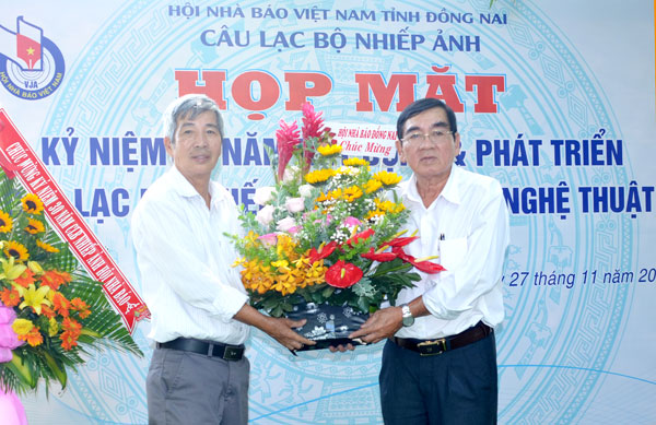 Phó chủ tịch Hội Nhà báo tỉnh Đỗ Trung Tiến (trái) tặng hoa chúc mừng CLB Nhiếp ảnh báo chí và nghệ thuật