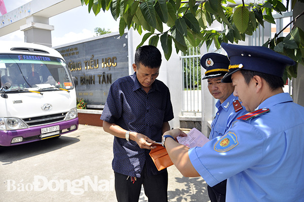 Lực lượng chức năng kiểm tra phù hiệu, đăng kiểm một xe tham gia đưa đón học sinh tại Trường tiểu học Long Bình Tân (TP.Biên Hòa). Ảnh: D.Ngọc