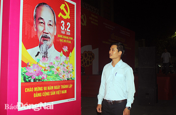 Họa sĩ Phạm Thanh Sinh bên tác phẩm tranh cổ động tấm lớn chào mừng 90 năm Ngày thành lập Đảng.  Ảnh: L.NA